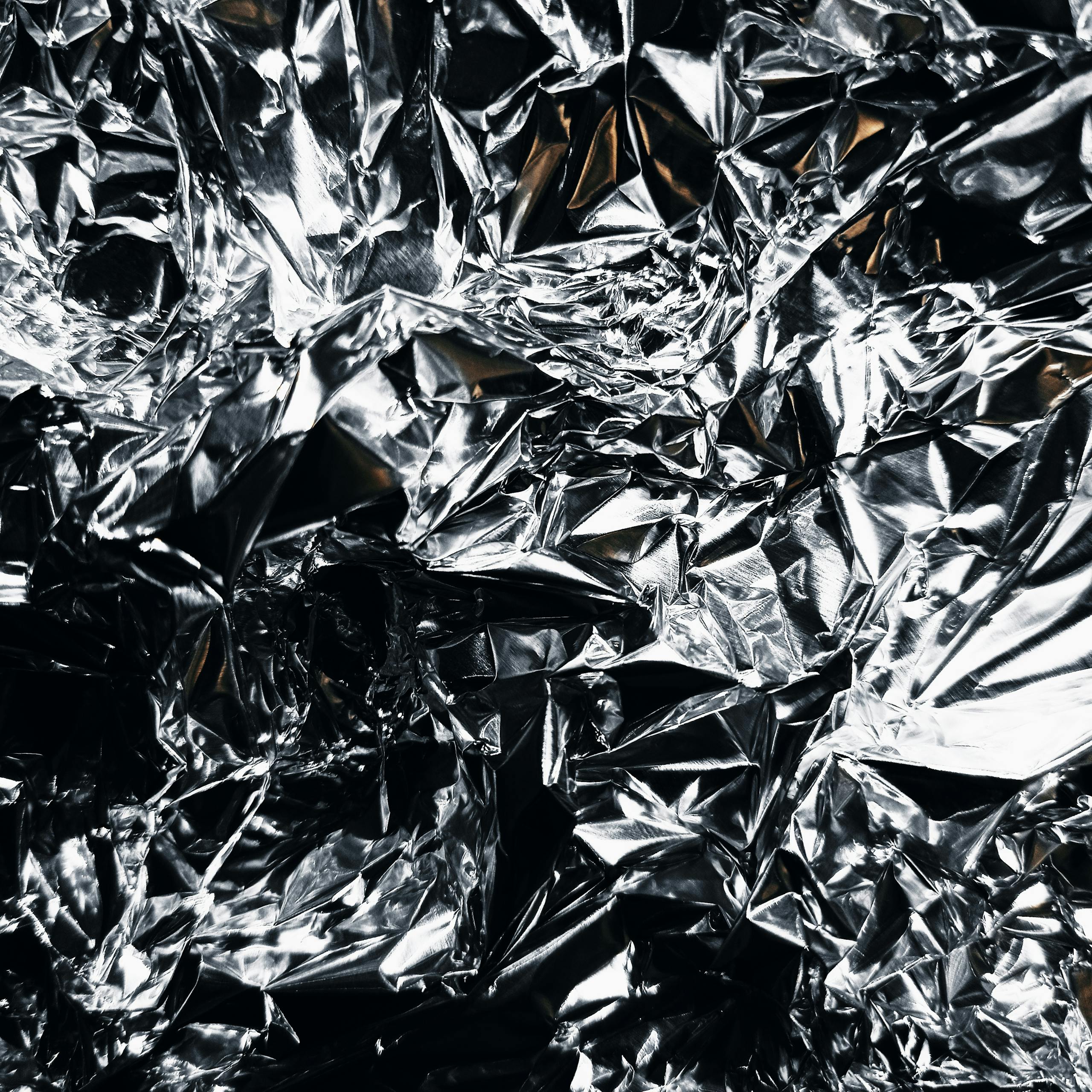 Close-up view of crumpled shiny silver aluminum foil showcasing detailed textures.