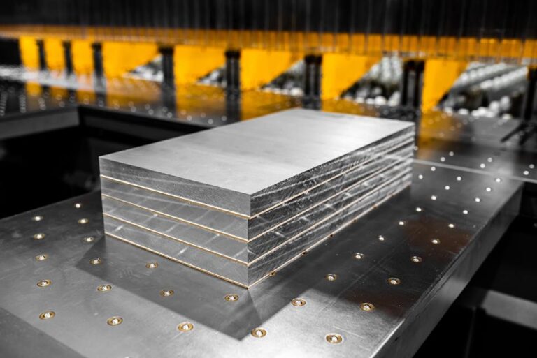 Ułożone warstwowo arkusze blachy aluminiowej na stole maszyny z perspektywy